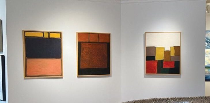 Drie abstracte schilderijen verlicht in een lichte galerieruimte
