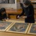 Twee medewerkers bekijken ingelijste kunstwerken voor conditiecontrole